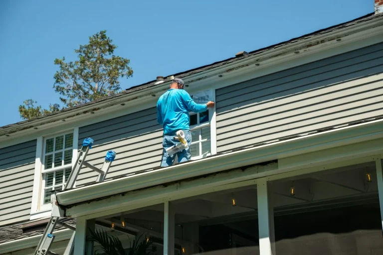 Painter working on a house exterior from a ladder